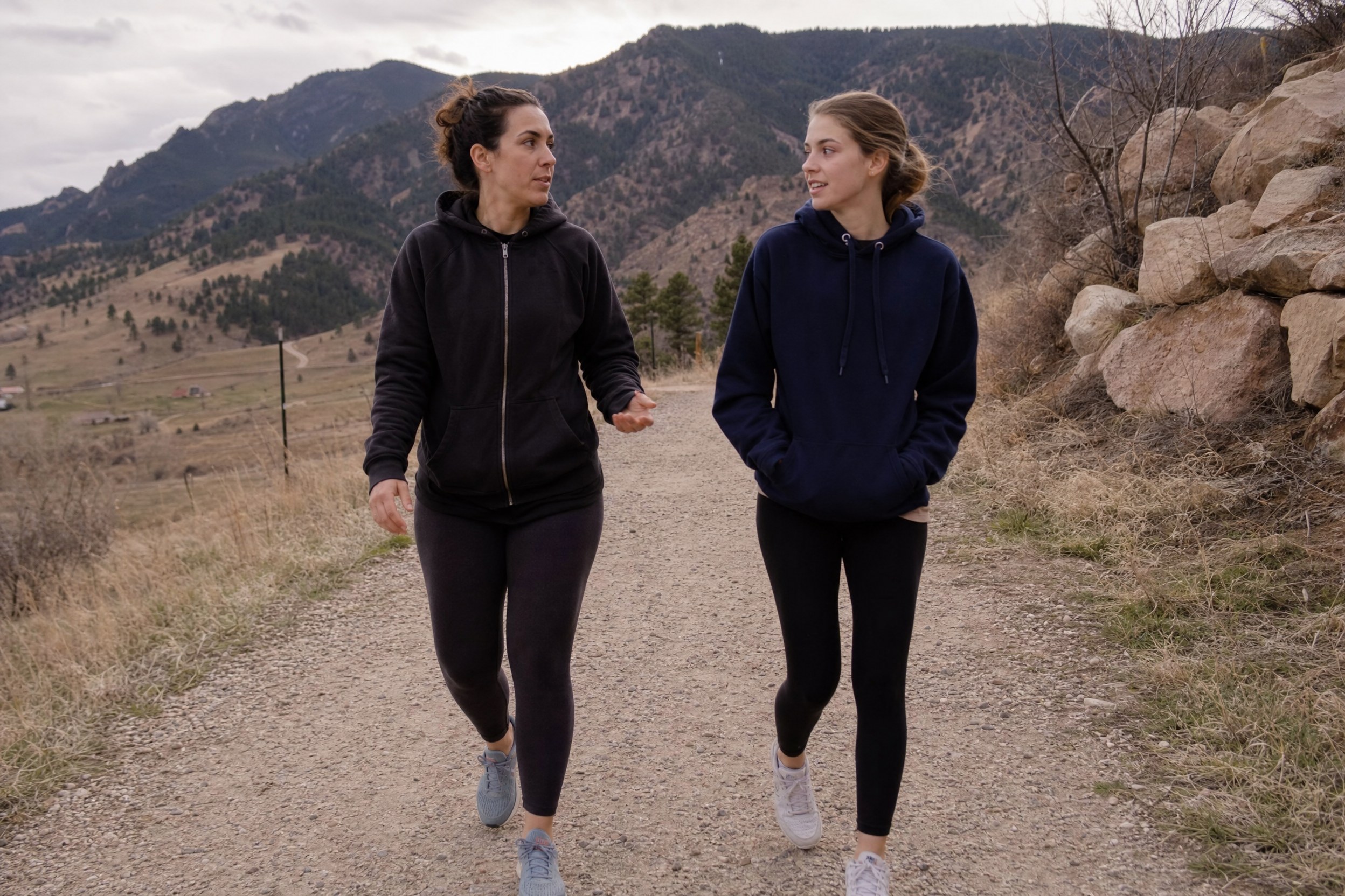 adhd-trail-walk-mentor A female mentor and a teenage girl walking side by side on a gravel trail near Boulder